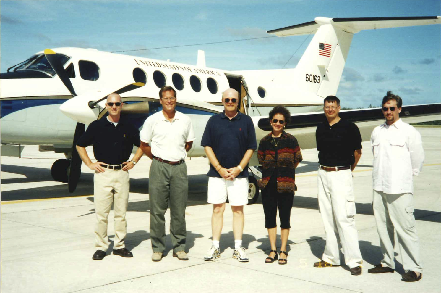 Ambassador Wills and others stand in front of a small plane labeled "United States of America"