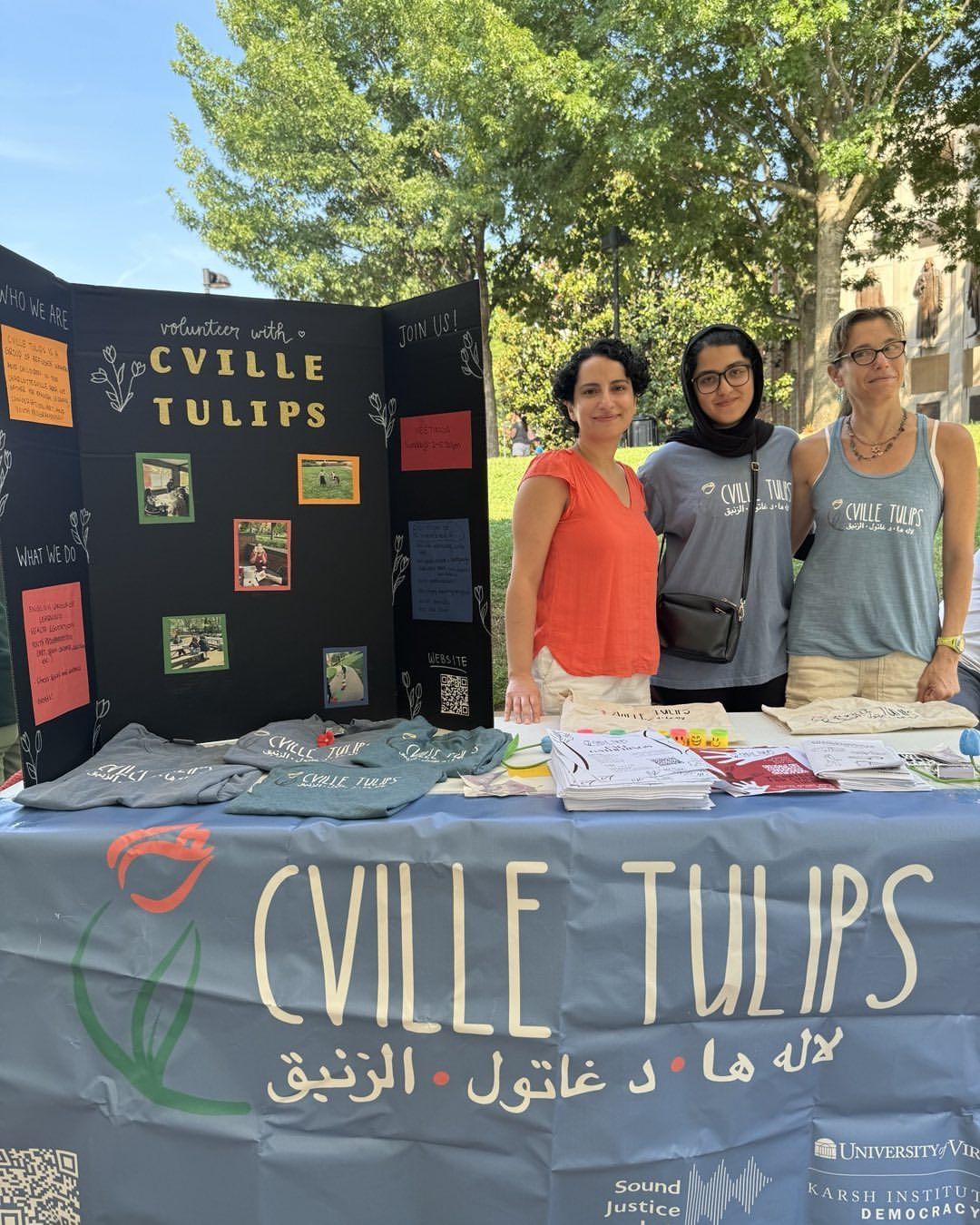 Marjan Omranian, Akbarzada, and Bonnie Gordon pose behind a table with a Cville Tulips banner