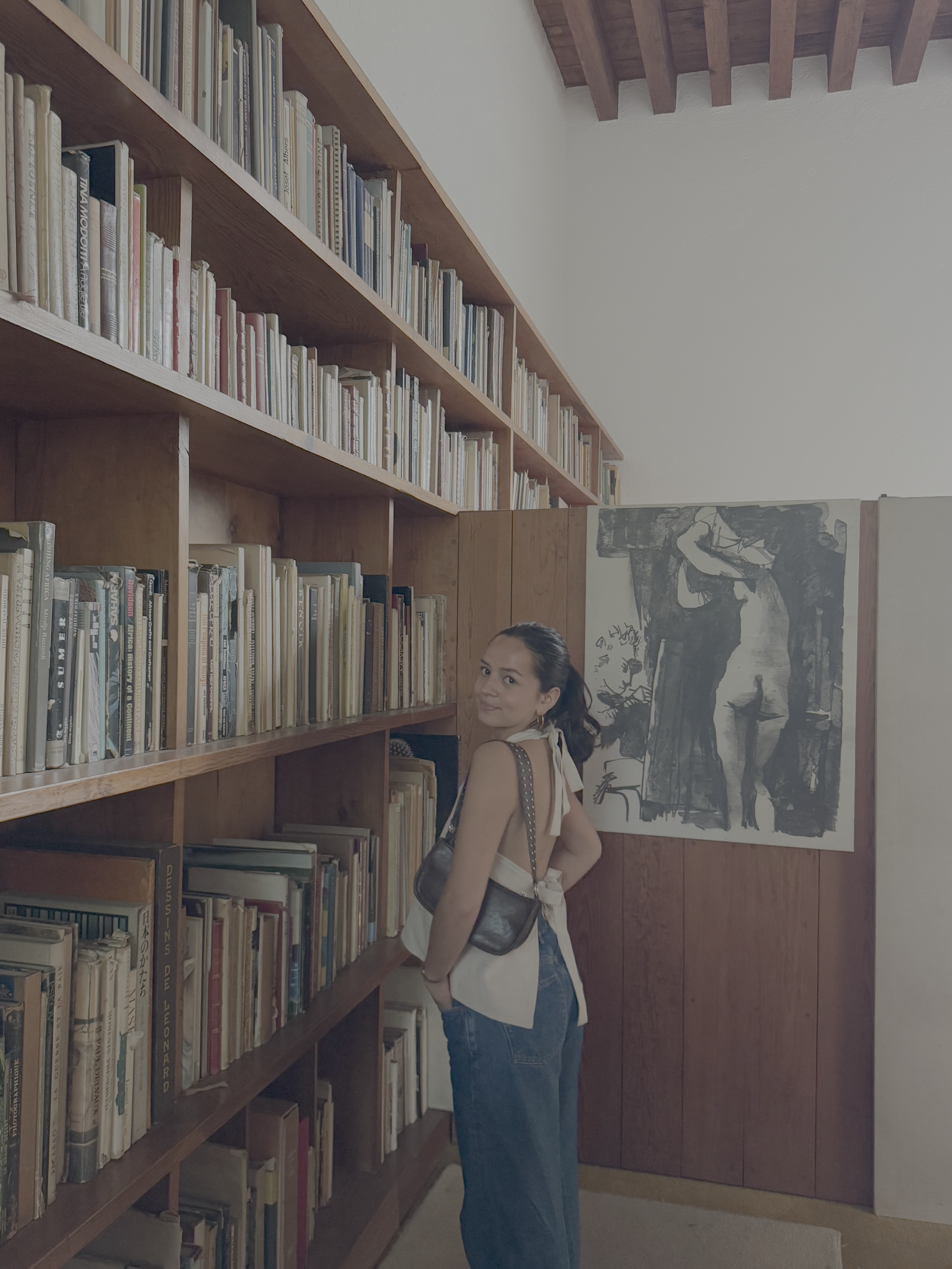 Gonzalez stands turning back towards the camera in front of a wall of bookshelves