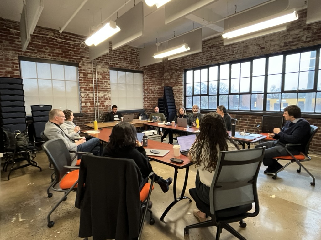 People talk seated around a table indoors