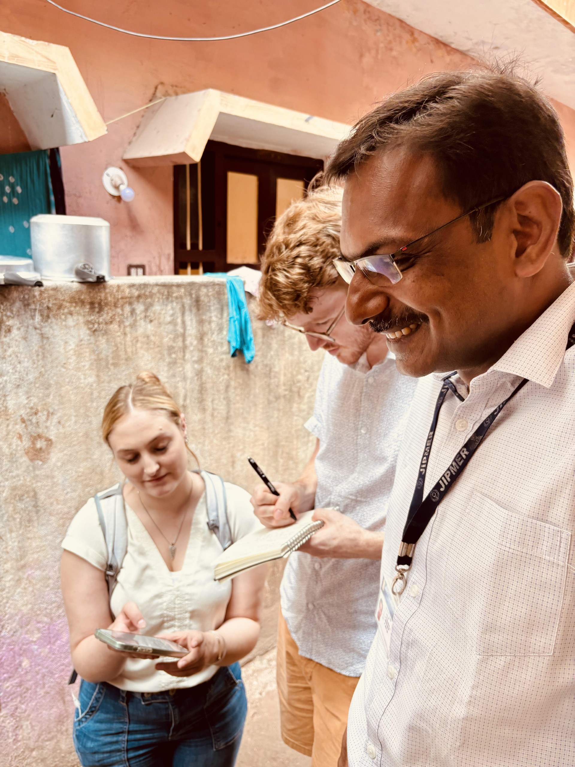 Sack writes down something shown to him by woman, man smiles in foreground.