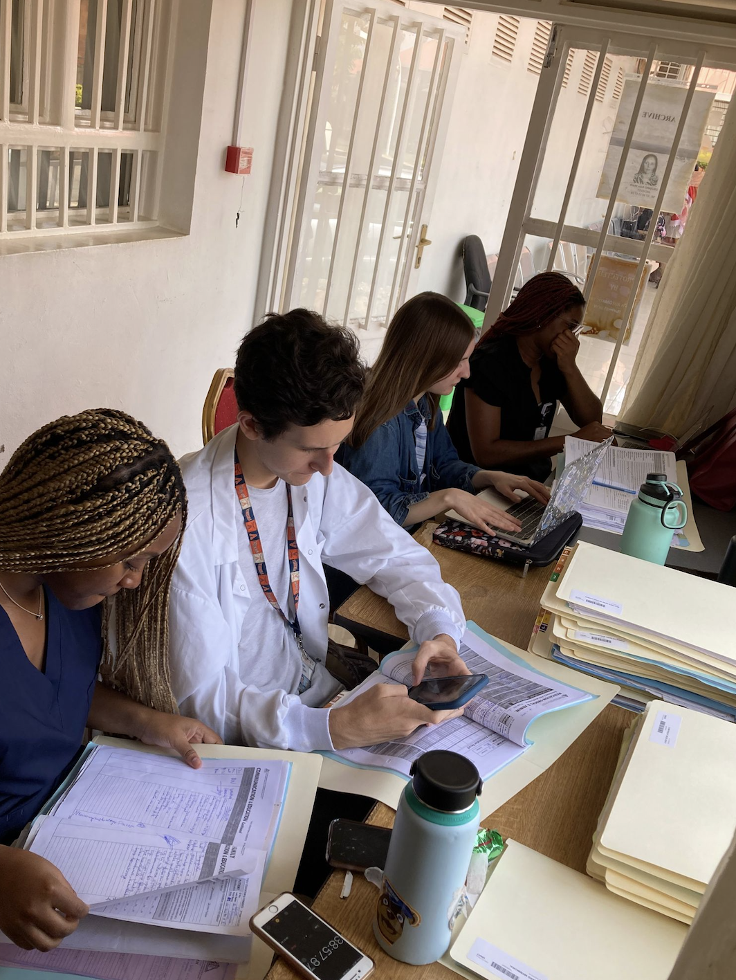 From right to left, Dazhanae Houston, Owen Selden, Shaina Twardus, and Kimberely Duru are reading patient records and evaluating where information in their surveys are located in the files at the University Teaching Hospital of Kigali’s (CHUK) medical archive. 