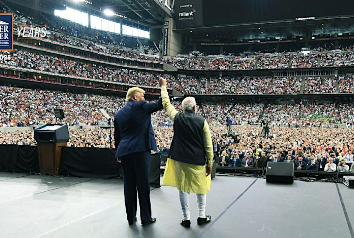 Trump and Modi raise hands held together in front of a cheering crowd