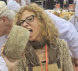 Buster pretending to bite into the side of a wheel of cheese.