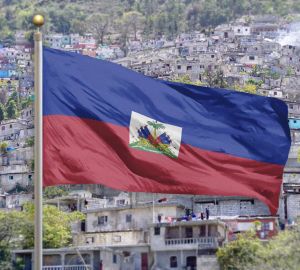 Haitian flag billowing with buildings of Port-au-Prince in the background