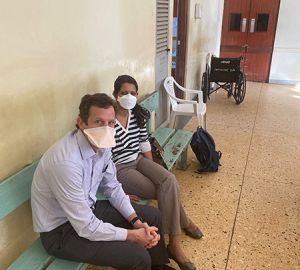 Josh Easter and Amita Sudhir Seated on a Bench Inside Hospital in Kenya