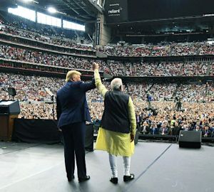 Trump and Modi raise hands held together in front of a cheering crowd